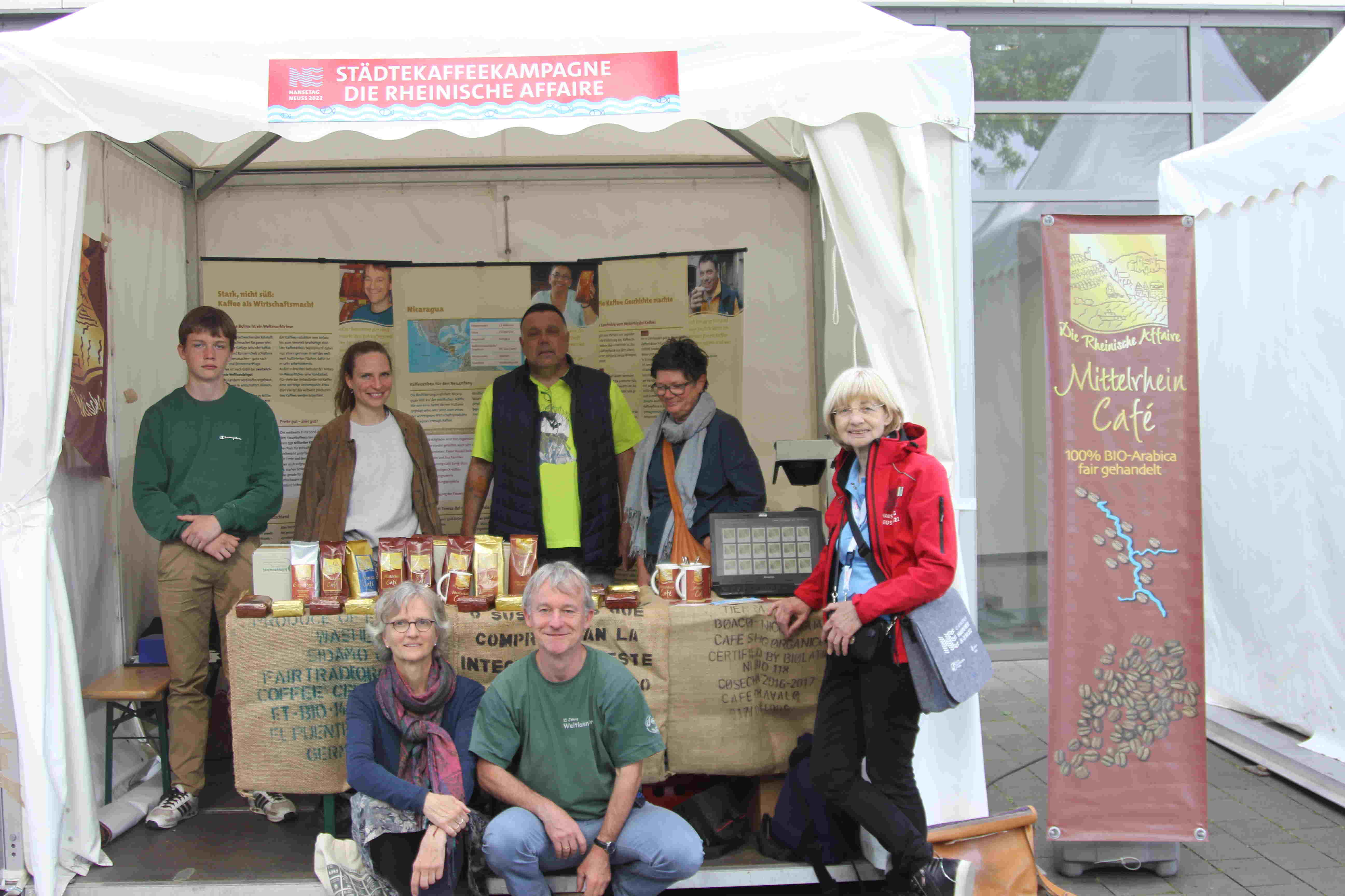 Ein Gruppenbild von Vertreterinnen und Vertretern der Rheinischen Affaire, umrahmt von Ausstellung und Kaffees, am Romaneum in Neuss Ein Gruppenbild von Vertreterinnen und Vertretern der Rheinischen Affaire, umrahmt von Ausstellung und Kaffees, am Romaneum in Neuss